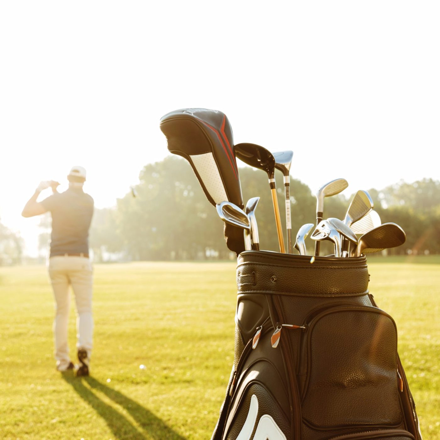 Back view of a male golfer swinging golf club and following shot in the air