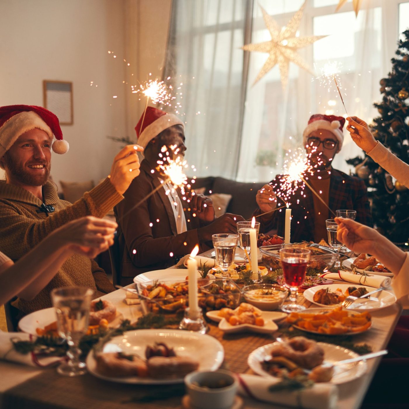 Group of people raising glasses while enjoying Christmas dinner at home