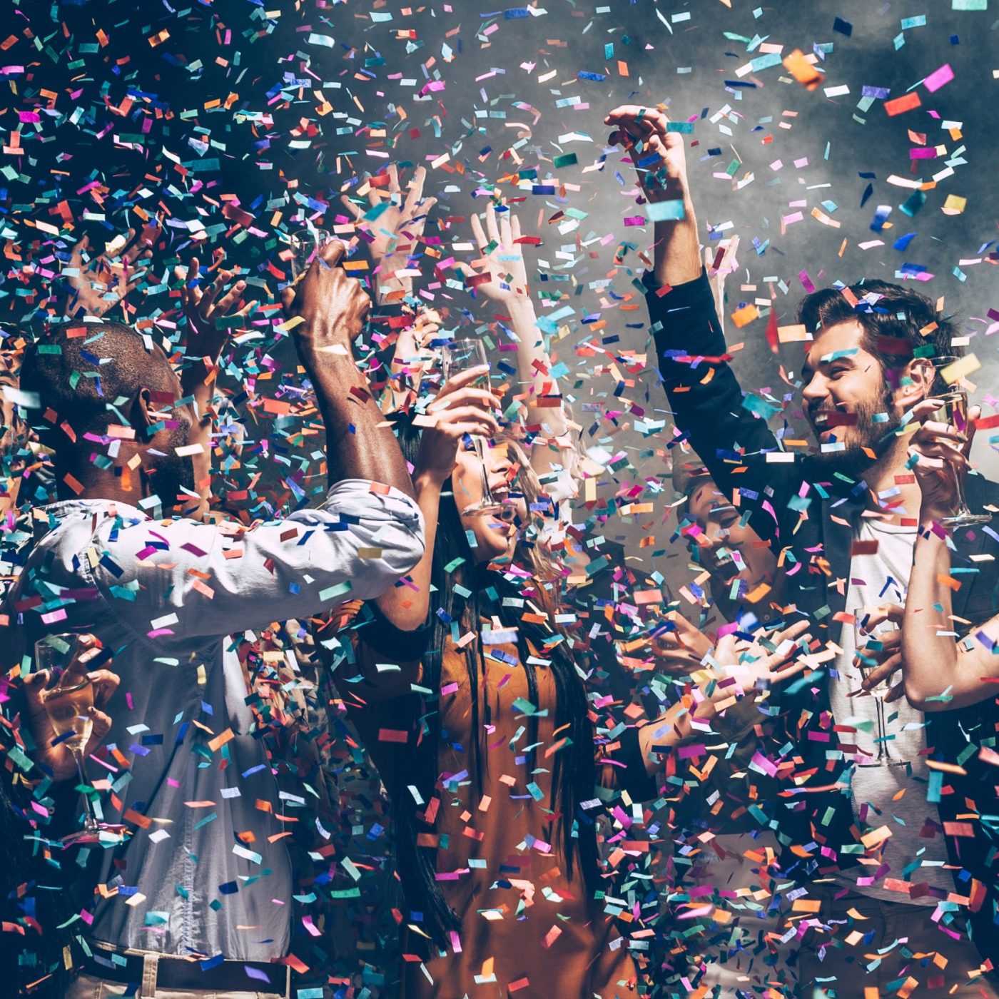 Confetti fun. Group of beautiful young people throwing colorful confetti while dancing and looking happy